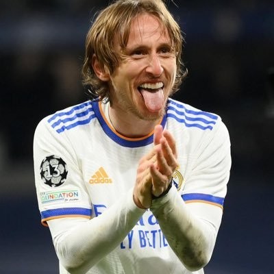 alt="Luka Modrić, Real Madrid's iconic midfielder, in his white kit, perhaps waving to fans or celebrating a past triumph, symbolizing his illustrious 13-year career and emotional departure from the club."