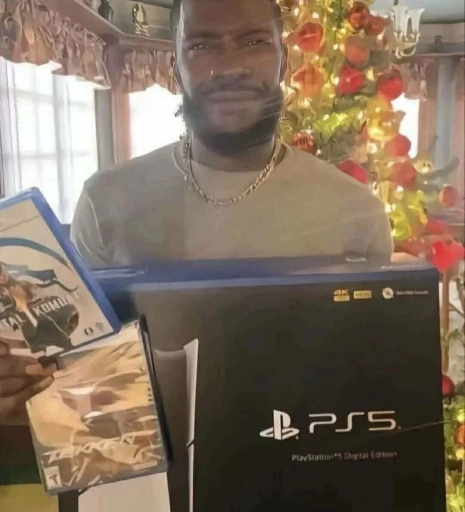 A man holding a PlayStation 5 Digital Edition box with two physical game discs, looking confused in front of a Christmas tree. Meme