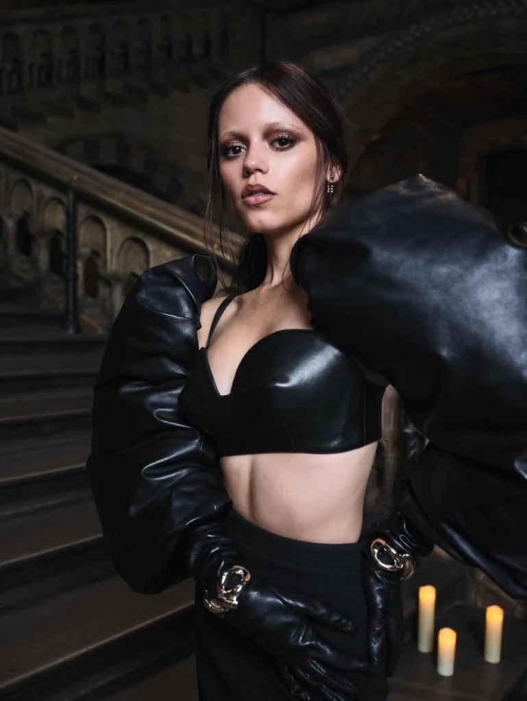 Jenna Ortega in character as Wednesday Addams, wearing her signature black dress on set.