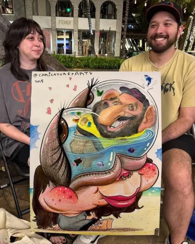 A woman with dark hair and a man with a beard are holding a large caricature drawing. The drawing depicts a woman with large lips and red cheeks, and a man with a beard in a fishbowl on top of her head.

