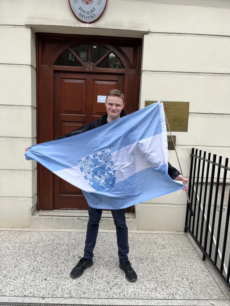 Daniel Jackson standing next to the Free Republic of Verdis flag in a forested area between Croatia and Serbia.