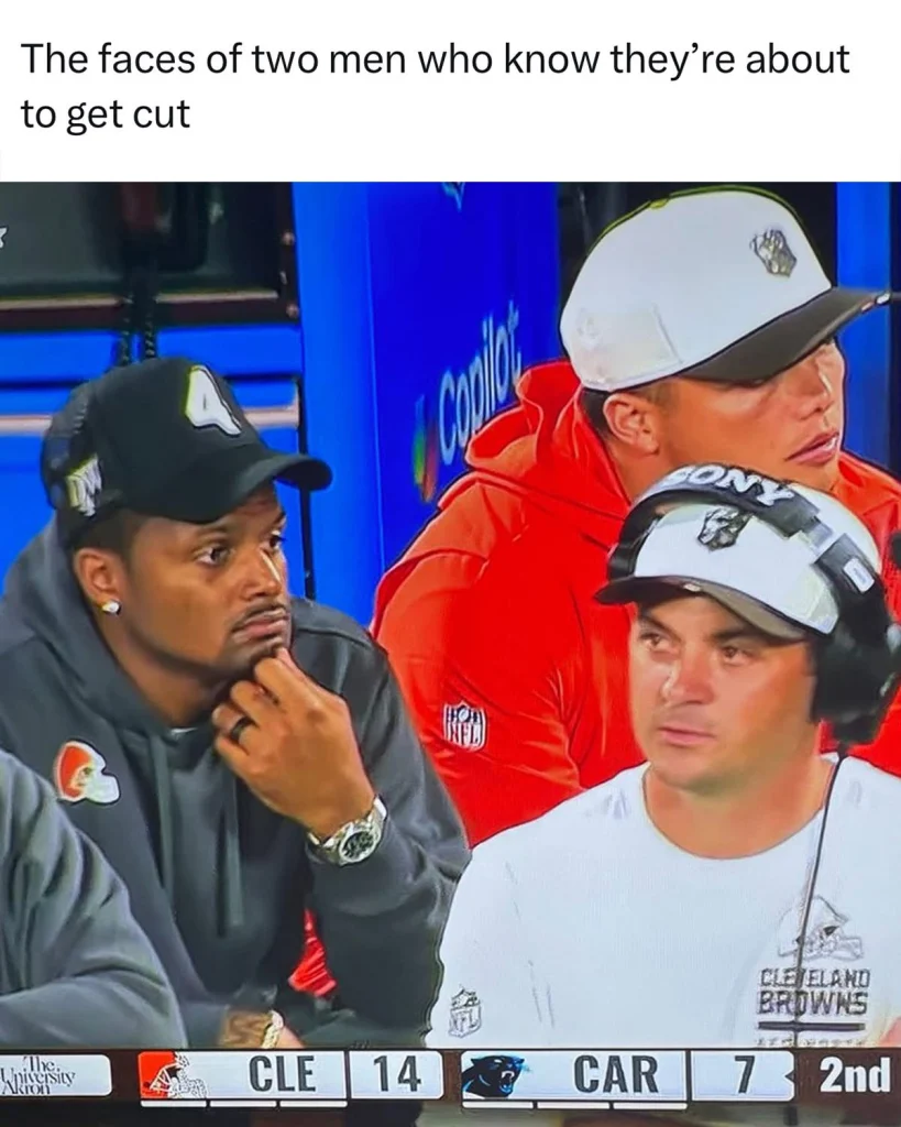 A meme featuring two men on a sideline looking thoughtful and concerned. The man on the left wears a gray Cleveland Browns hoodie and black cap, resting his chin on his hand. The man on the right sports a white “CLEVELAND BROWNS” t-shirt and a white helmet with a headset.