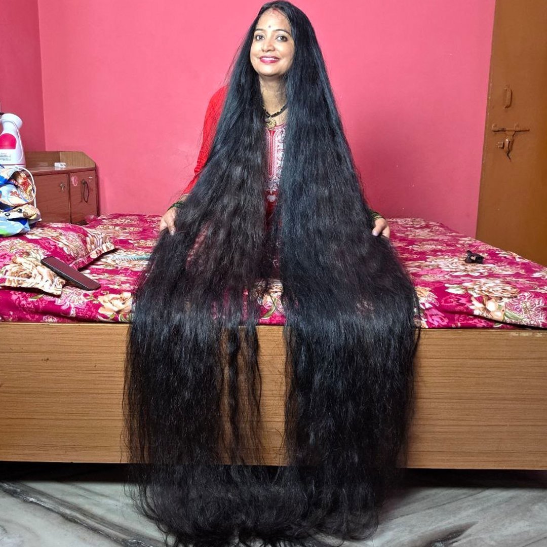 Renu Dhariyal sitting on a bed with her long hair cascading over the side and onto the floor